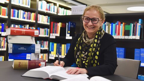 Monique Schnell Luchsinger schreibt an einem Tisch mit vielen Rechtsbüchern.